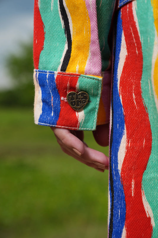 Detalle del puño con botón corazón y las rayas multicolor de la Chaqueta Denim El Río – Ale Ardila Studios