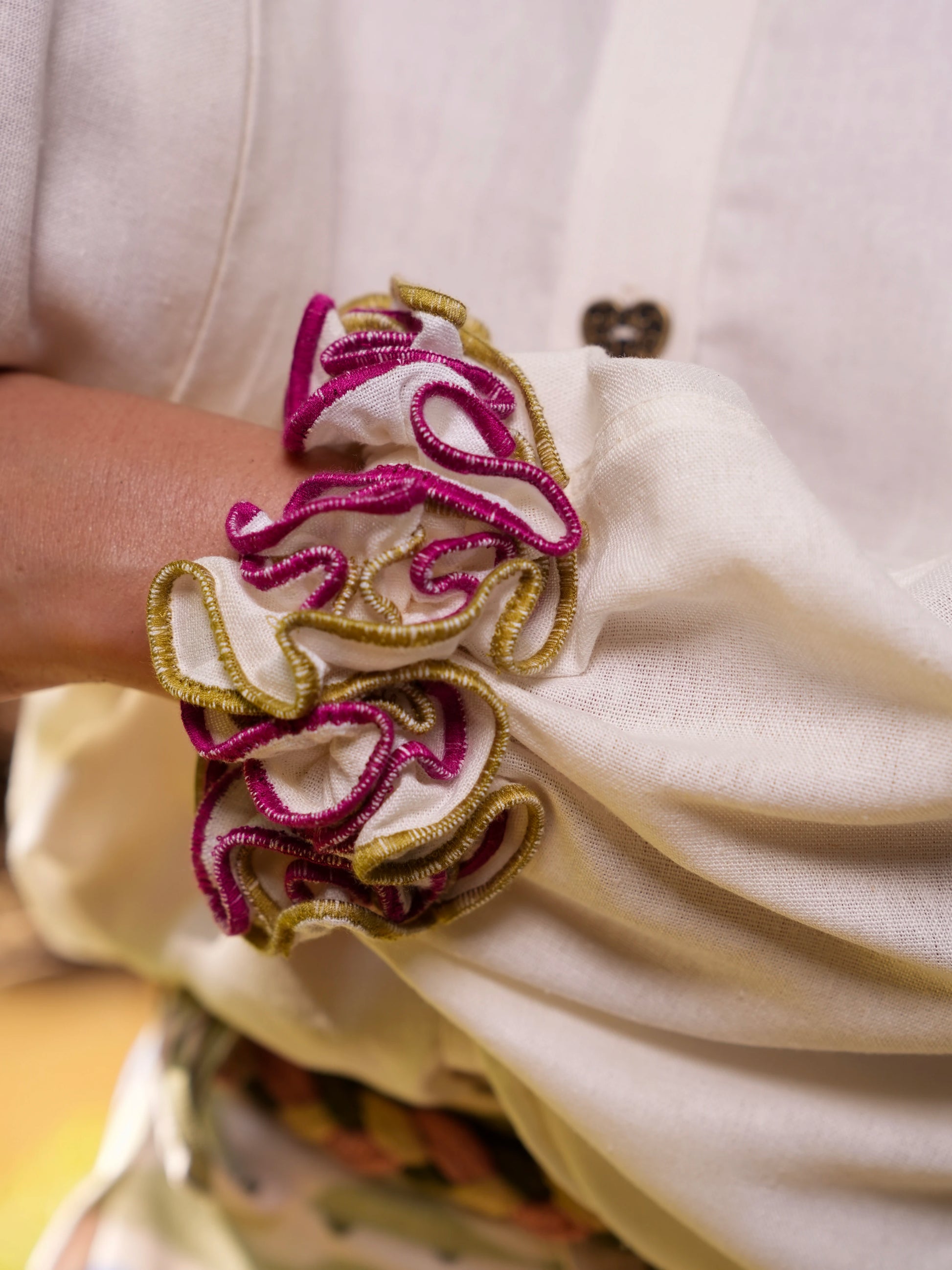 Primer plano del volante fucsia y dorado en el puño de la Blusa Travesía en lino crema – Ale Ardila Studios
