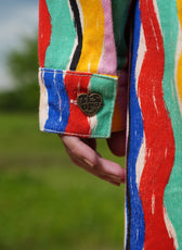 Detalle del puño con botón corazón y las rayas multicolor de la Chaqueta Denim El Río – Ale Ardila Studios
