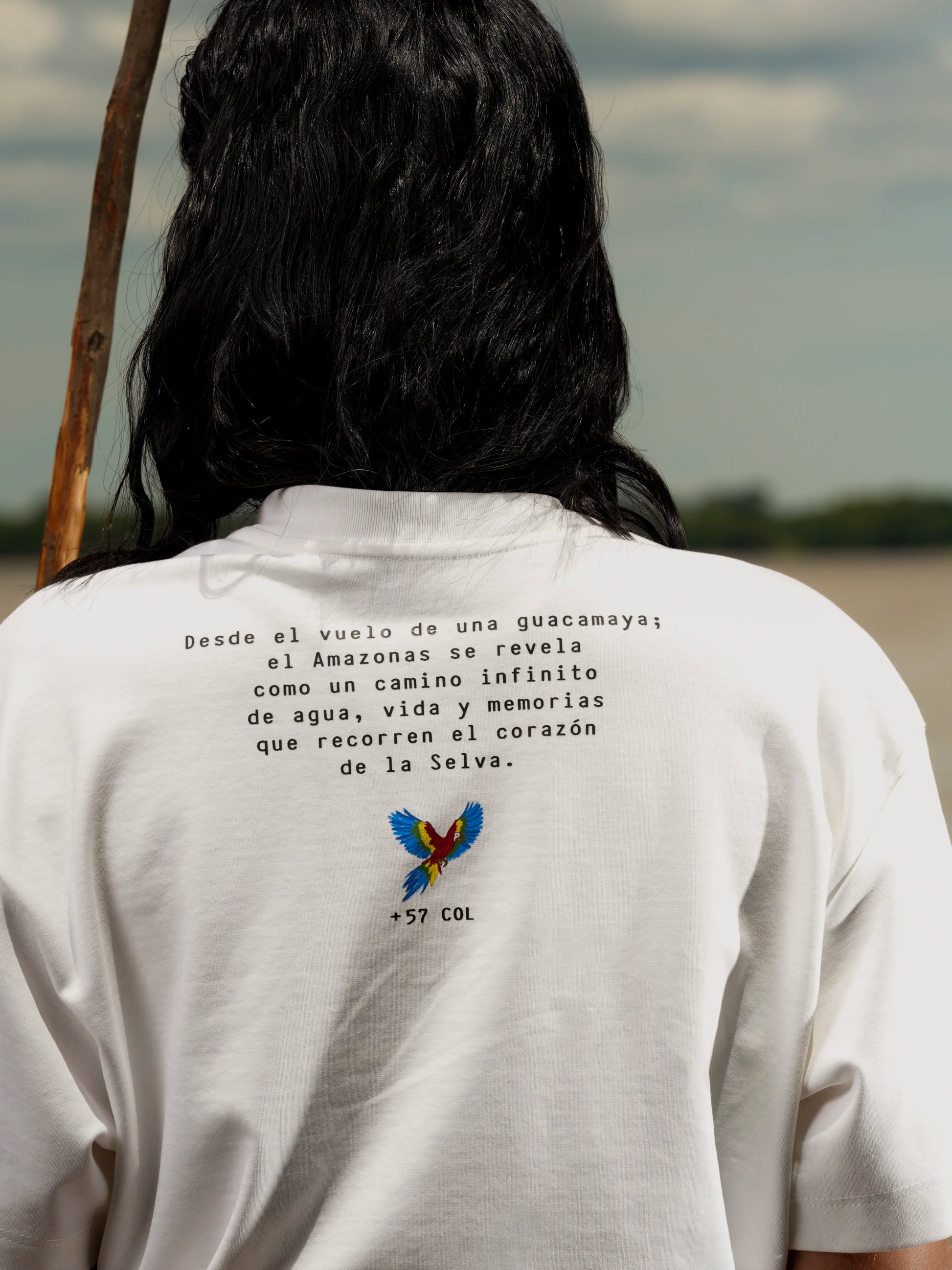 Vista de espalda de la Camiseta Amazonas con el mensaje de la colección y una guacamaya – Ale Ardila Studios