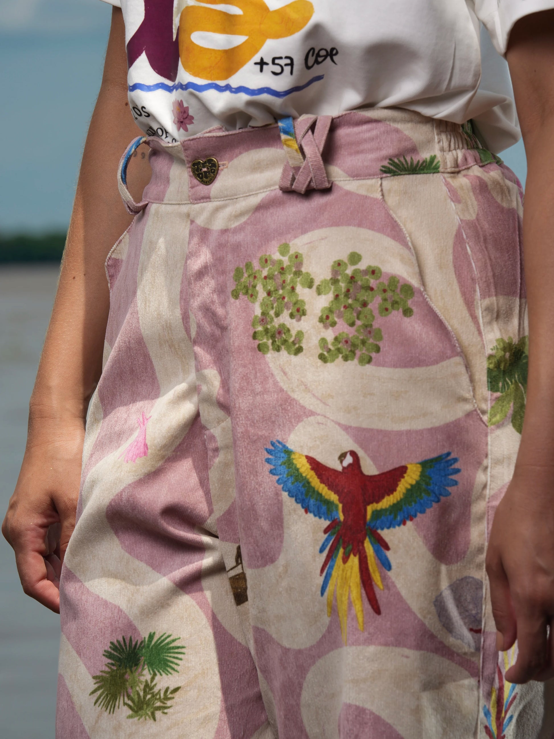 Detalle frontal del bolsillo y el estampado de guacamayas del Pant Cielo Amazónico – Ale Ardila Studios